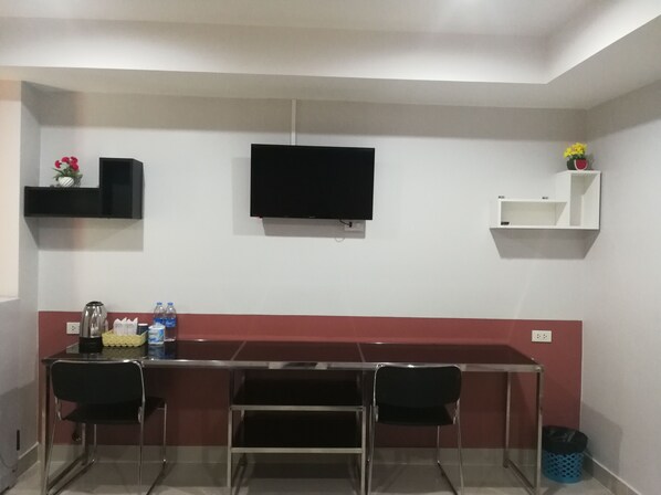 A small, modern room with a kitchenette, a flat-screen TV, and two chairs.