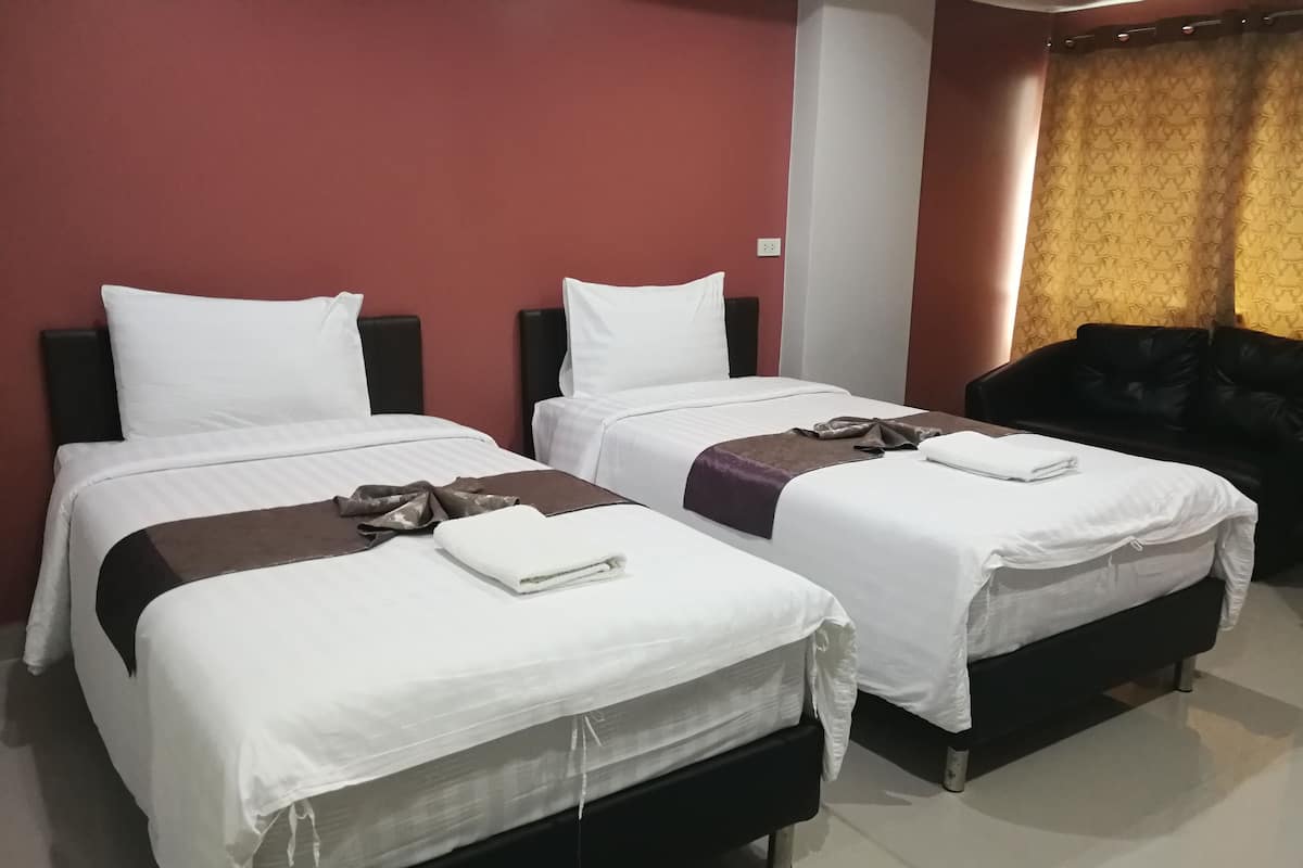 A hotel room with two beds, a black leather sofa, and a red accent wall.
