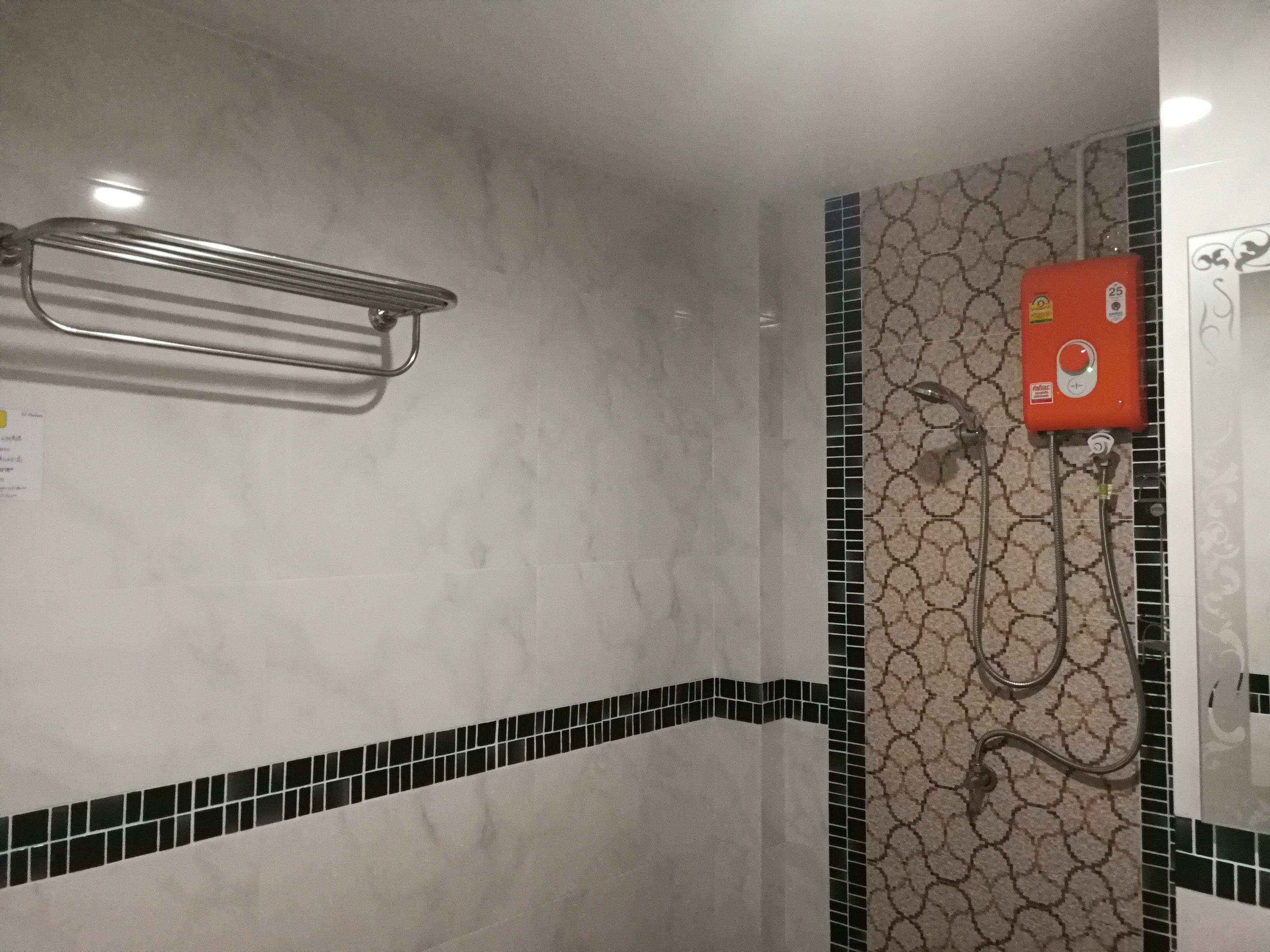 A bathroom with a shower, a towel rack, and a wall-mounted heater.