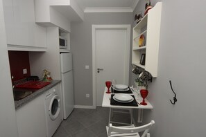 A compact kitchen with a washing machine, a microwave, and a dining area with a table set for two.