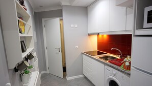 Uma cozinha compacta com armários brancos, micro-ondas embutido, máquina de lavar e backsplash com azulejos vermelhos.