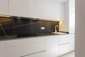 A modern kitchen with a black countertop, white cabinets, and a stainless steel range hood.