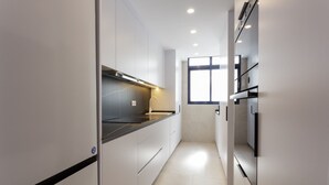 Eine moderne Küche mit weißen Schränken, einer schwarzen Arbeitsplatte und einem Fenster, das für natürliches Licht sorgt.