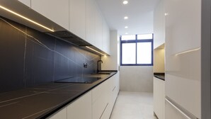 Una cocina moderna con armarios blancos, encimera negra y una ventana que deja entrar luz natural.