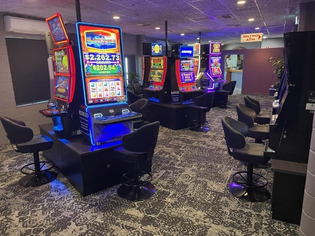 A casino area with slot machines and bar stools.