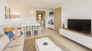 Un salon moderne comprenant un canapé, une table basse, un téléviseur, un coin repas et une cuisine.