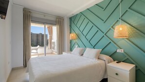 Une chambre d’hôtel moderne avec un grand lit, une table de chevet blanche et un mur d’accent vert.