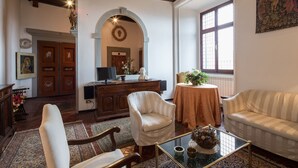 A traditional living room with a fireplace, a television, and a dining area with a table and chairs. - 3BR luxury apt, walk to downtown Cortona, and amazing view over the town hall (Cortona)