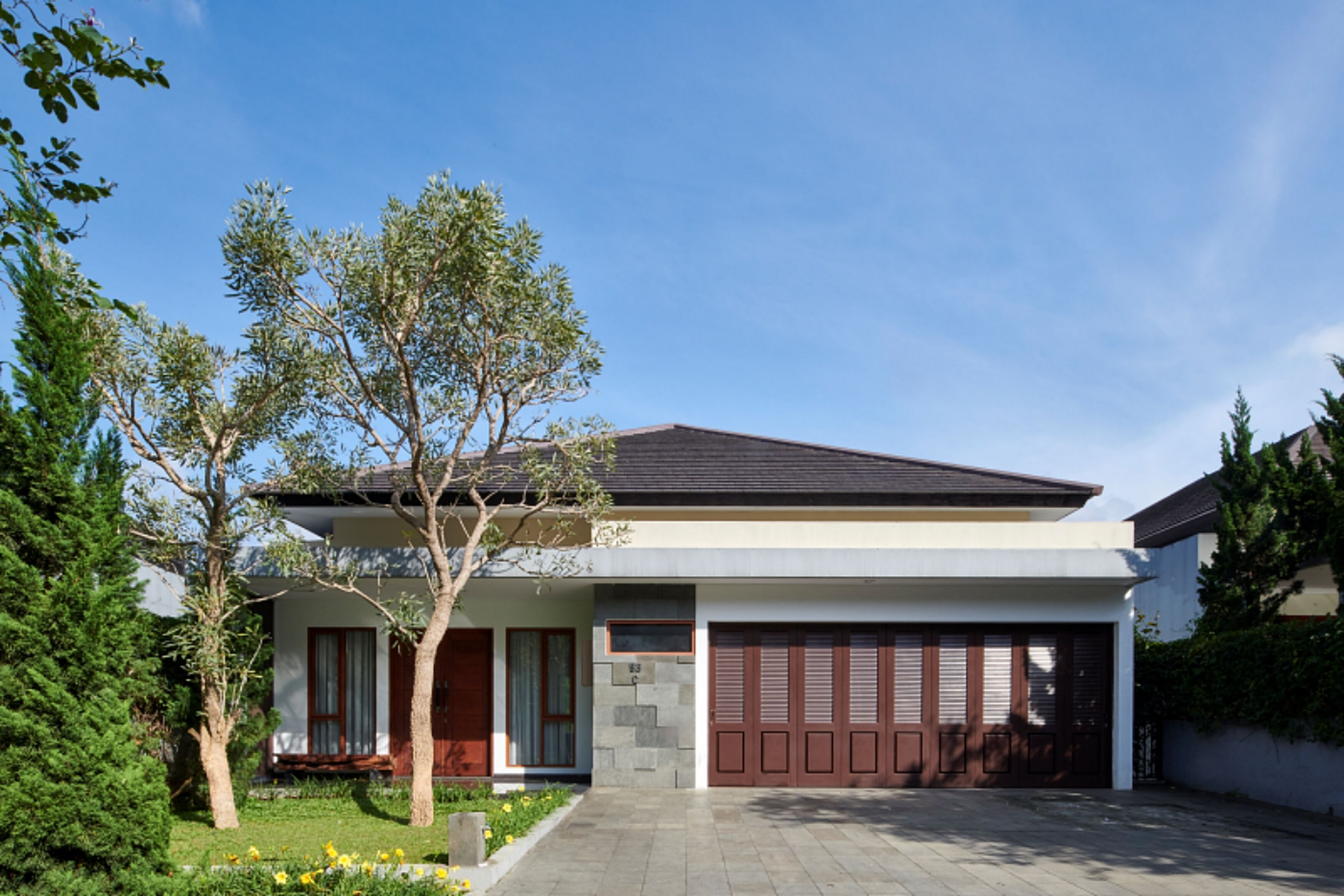 A modern two-story house with a garage, a well-maintained lawn, and a clear blue sky.
