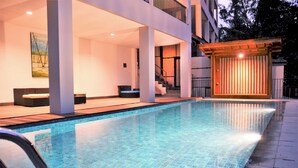 A swimming pool with tiled flooring, a covered seating area, and a building with a staircase. - Magenta Villa 6 BR With Pool Movieroom Billiard (Bandung)