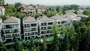 A multi-story hotel with balconies, a swimming pool, and lush greenery surrounding the buildings. - Magenta Villa 6 BR With Pool Movieroom Billiard (Bandung)