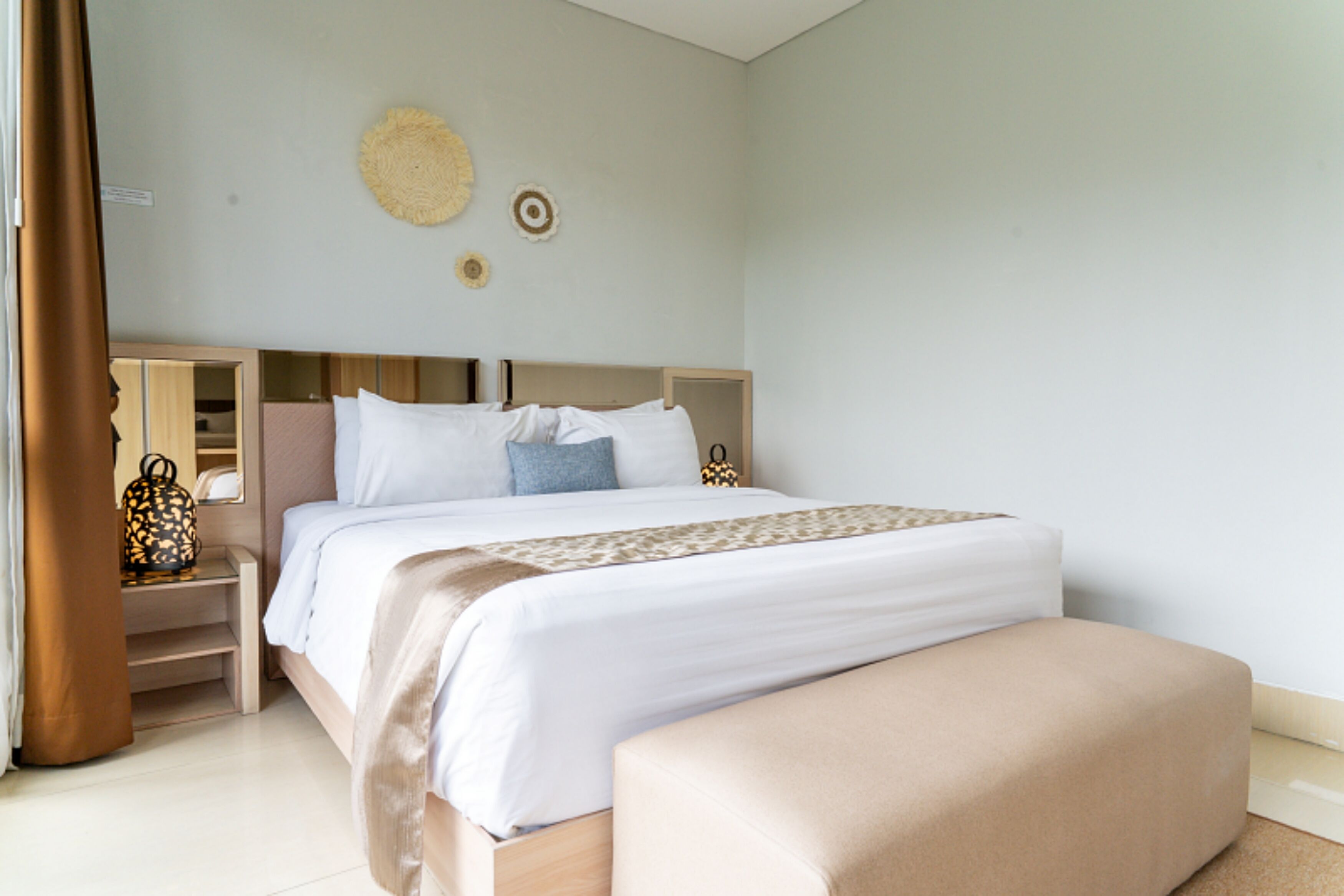 A bedroom with a bed, bedside tables, a bench, and wall decor.