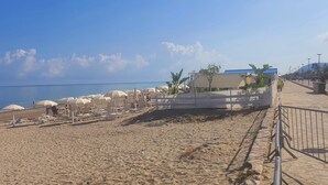 A beach with umbrellas, lounge chairs, and a fence along the water. - **** RUMAH SAYA ****  Balinese house by the sea (Campofelice di Roccella)