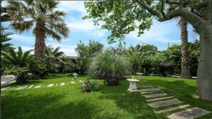 A well-maintained garden with a variety of plants, a stone pathway, and a clear sky. - **** RUMAH SAYA ****  Balinese house by the sea (Campofelice di Roccella)