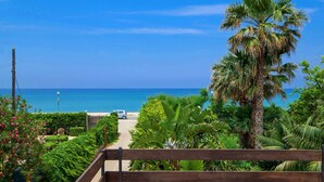 A balcony with a view of a beach and palm trees. - **** RUMAH SAYA ****  Balinese house by the sea (Campofelice di Roccella)