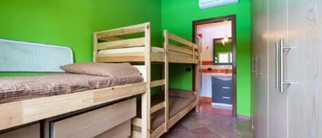 A room with bunk beds, a wooden wardrobe, and a green wall.