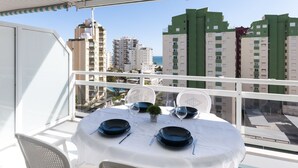 A balcony with a table set for two, overlooking a cityscape with high-rise buildings and a clear sky. - Beautiful condo family near to the beach. Pool / Wifi - only families (Playa de Gandía)