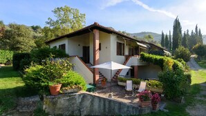 Une maison à deux étages dotée d’un patio, d’un espace salon extérieur et d’un jardin.