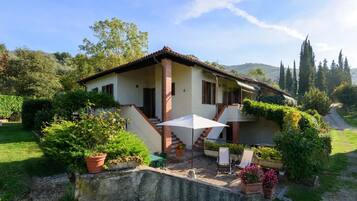 Una casa a due piani con patio, area salotto all'aperto e giardino.