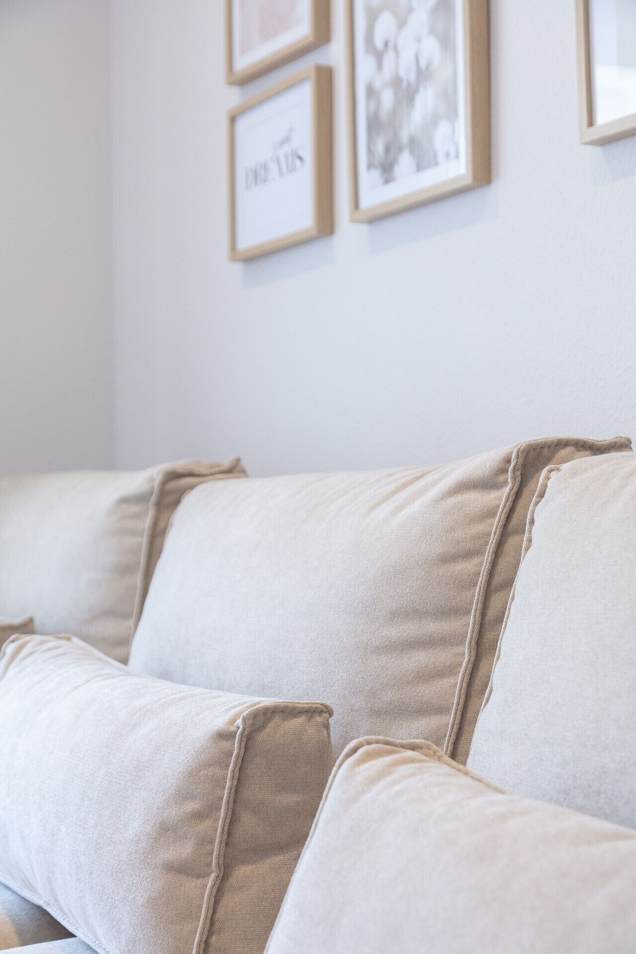A beige sofa with a textured fabric and a contrasting fabric accent.