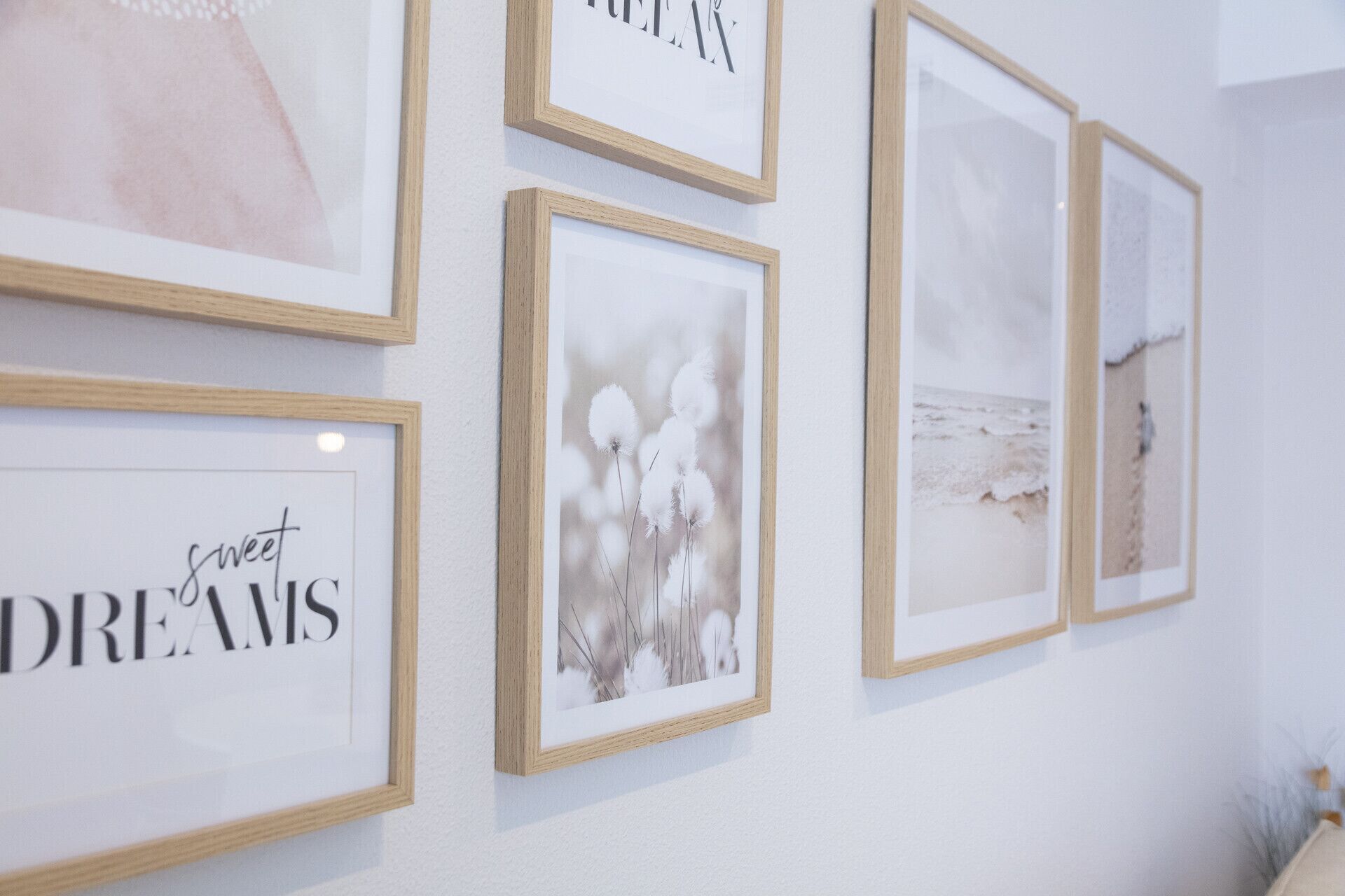 Una pared con varias fotos enmarcadas, incluyendo una escena de playa y una imagen floral.