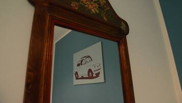 A mirror with a floral design on the top and a picture of a car on the mirror's surface.