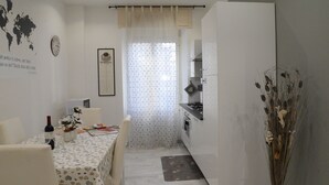 A compact kitchen with white cabinets, a dining area with a table set for two, and a decorative vase on the right. - At Casa di Rosa, your home a stone's throw from San Pietro ... (Roma)