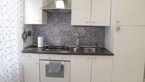 A kitchen with white cabinets, a tiled backsplash, a gas stove, and a stainless steel sink. - At Casa di Rosa, your home a stone's throw from San Pietro ... (Roma)