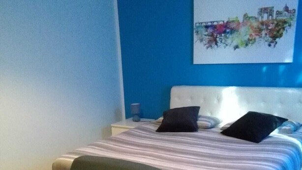 A bedroom with a bed, a chair, a nightstand, and a wall art piece. - At Casa di Rosa, your home a stone's throw from San Pietro ... (Roma)
