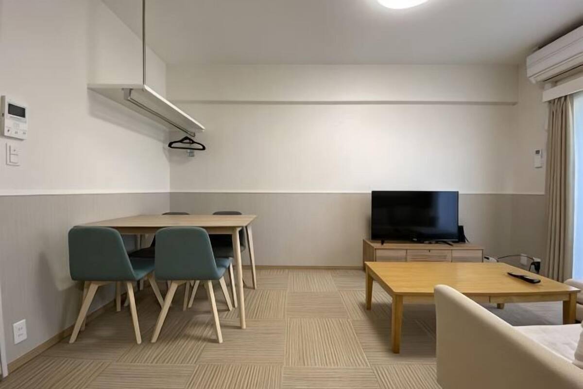 Habitación de hotel con una mesa de comedor, dos sillas, un televisor, una cama y una ventana.