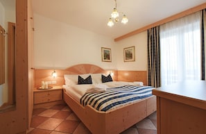 A wooden-framed bedroom with a bed, nightstands, and a window with curtains.