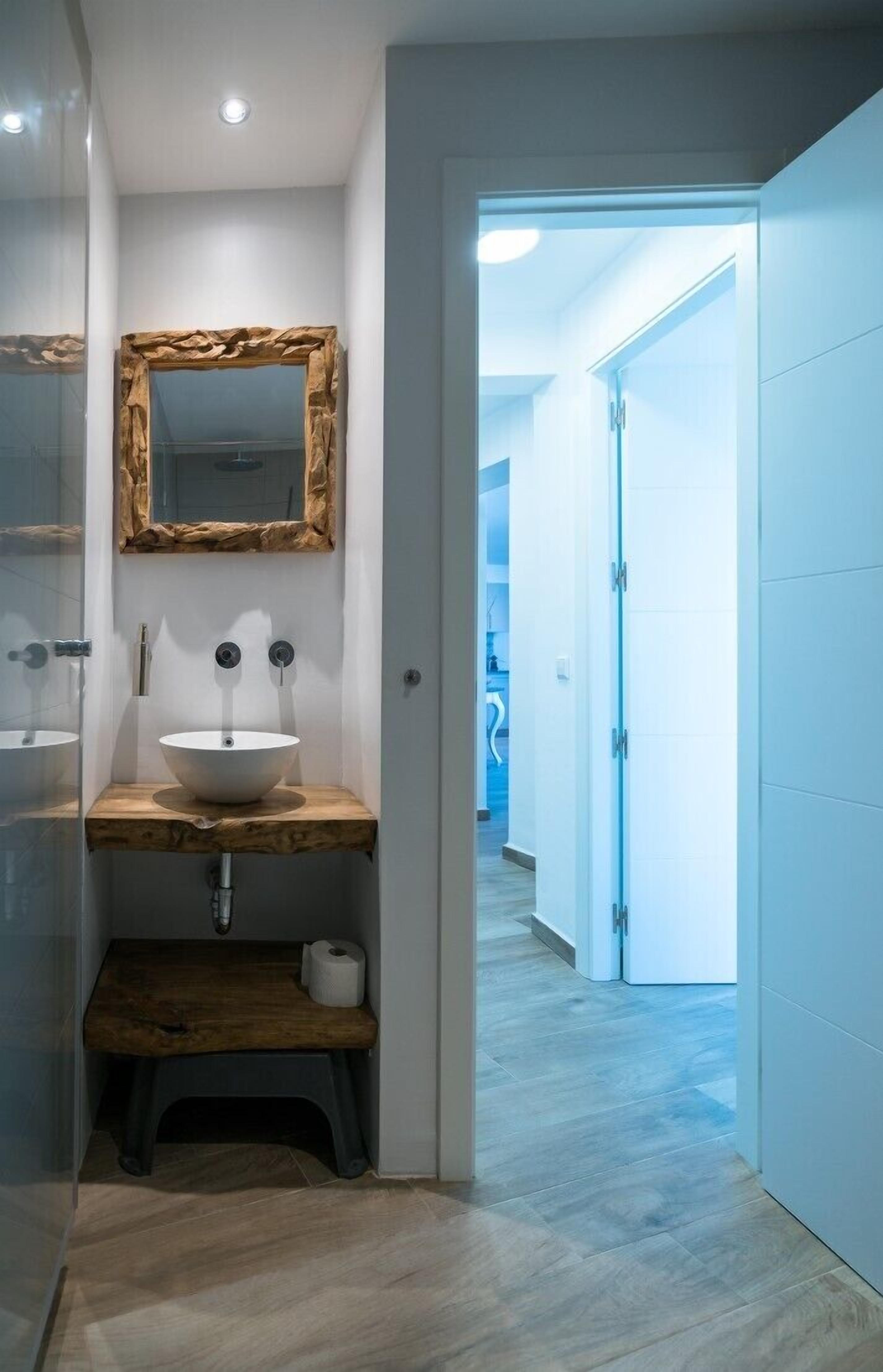 Ein modernes Badezimmer mit einem Holzbadschrank, einem großen Spiegel und einem weißen Waschbecken.