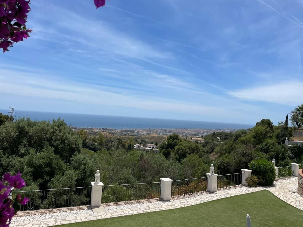 Ein angelegter Garten mit einem Kiesweg, einem weißen Zaun und Blick auf das Meer und die Ferne.