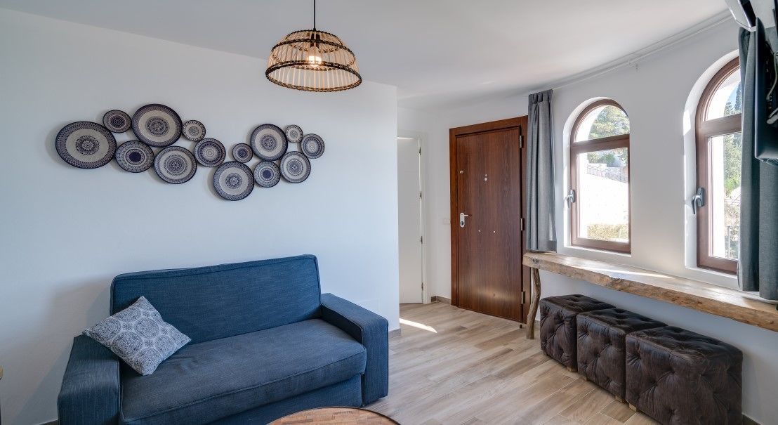 A modern living room with a blue sofa, a decorative wall art piece, and a wooden bench.