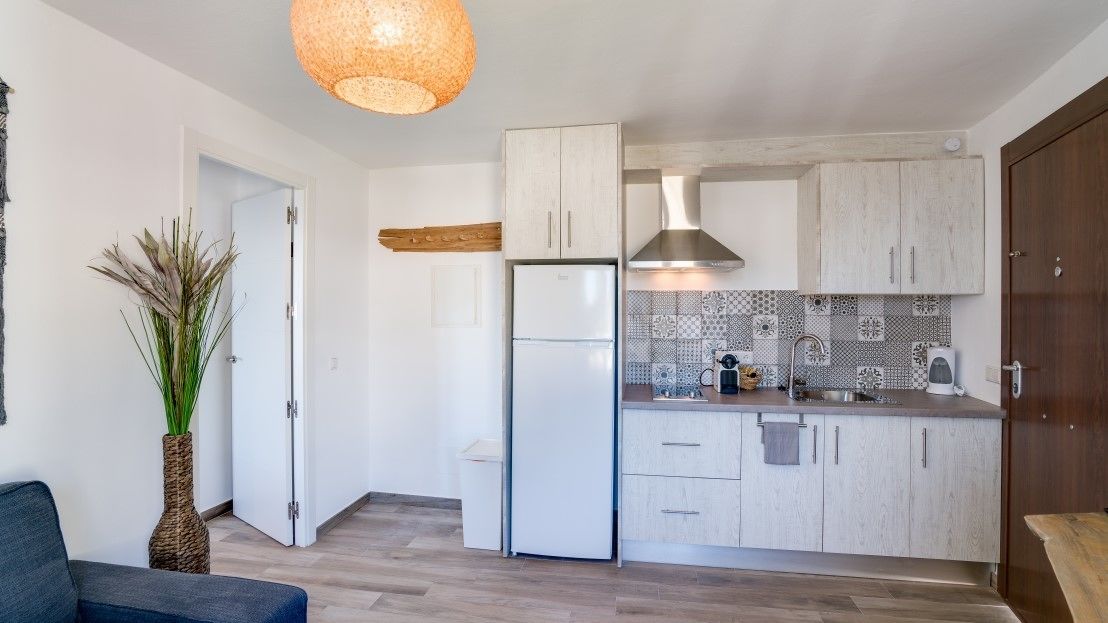Une cuisine moderne avec des meubles blancs, une hotte en acier inoxydable et un réfrigérateur blanc.