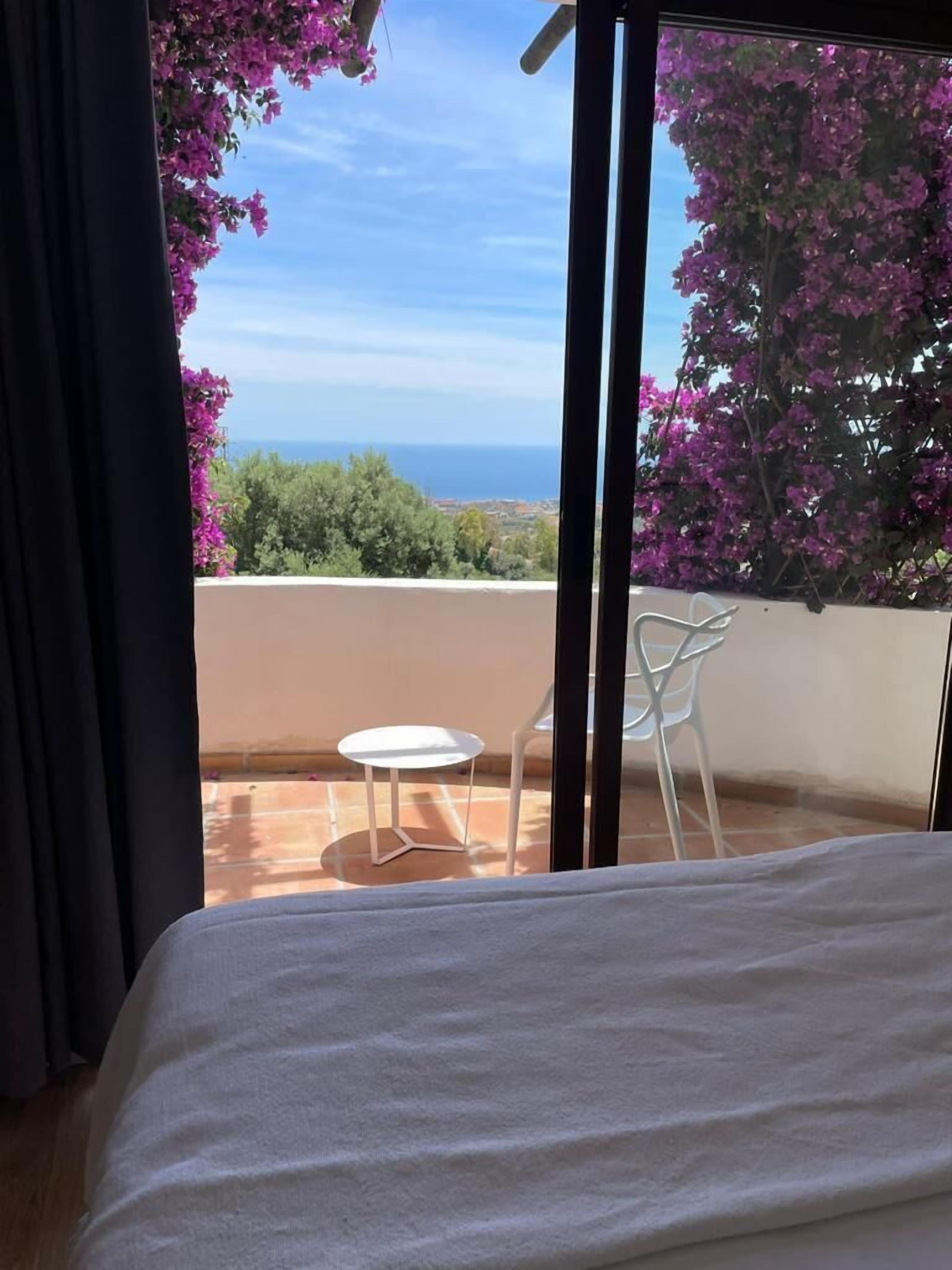 A balcony with a bed, a small table, and two chairs.