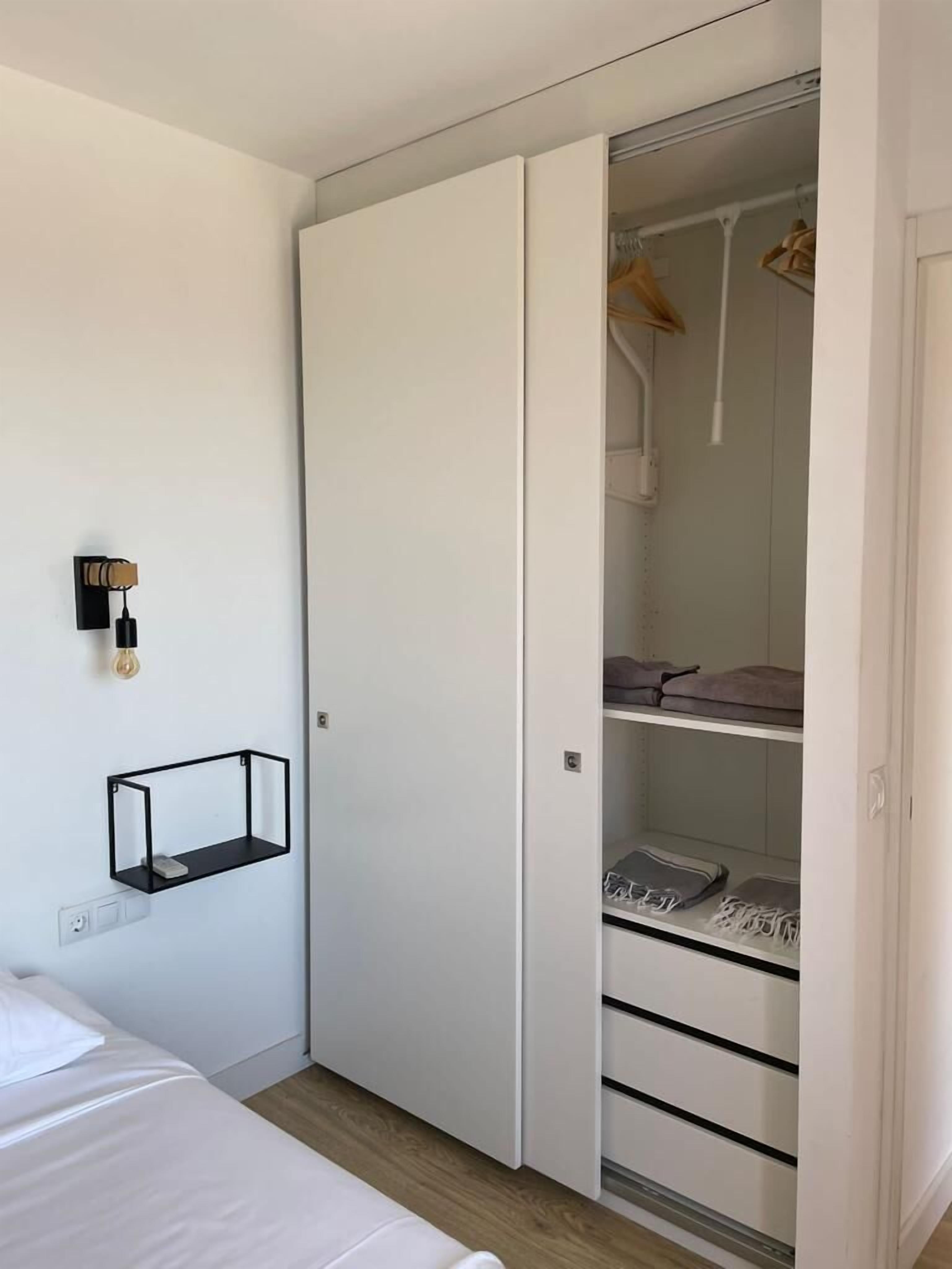 A bedroom with a bed, a white wardrobe, and a hanging light fixture.