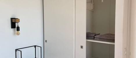 A bedroom with a bed, a white wardrobe, and a hanging light fixture.