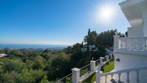 A balcony with a view of a coastal landscape, a white building with the number 4, and a clear blue sky. - Mijas Residence (Mijas)