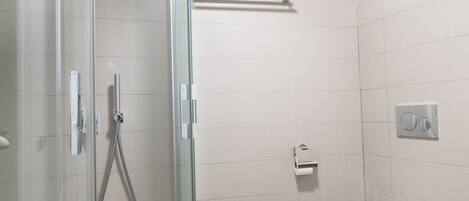 A modern bathroom with a glass-enclosed shower, a white toilet, and a wooden floor.