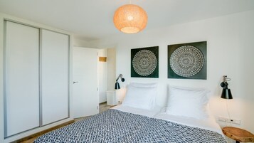 A bedroom with a bed, two wall-mounted lamps, and two circular wall art pieces.