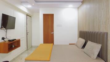 Un dormitorio con cama, televisión montada en la pared, mueble de madera y ventilador de techo.