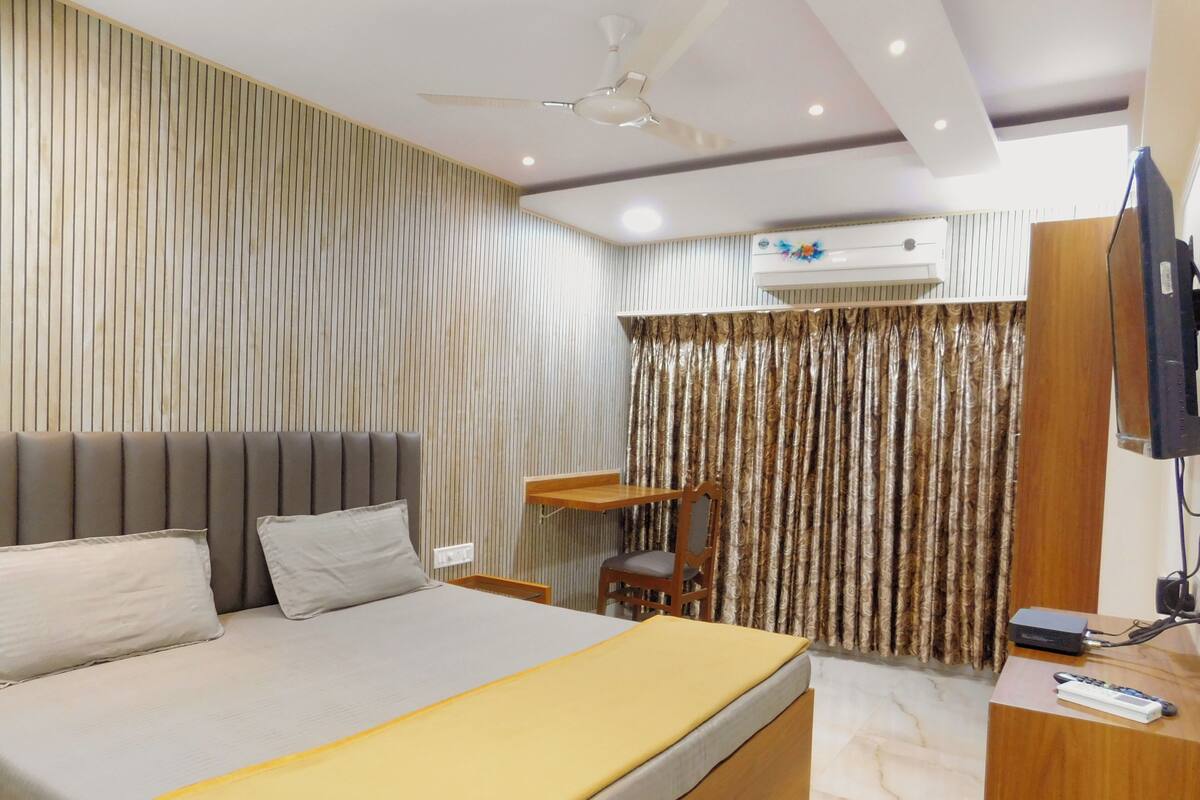 A modern hotel room with a large bed, a desk, a chair, and a television.