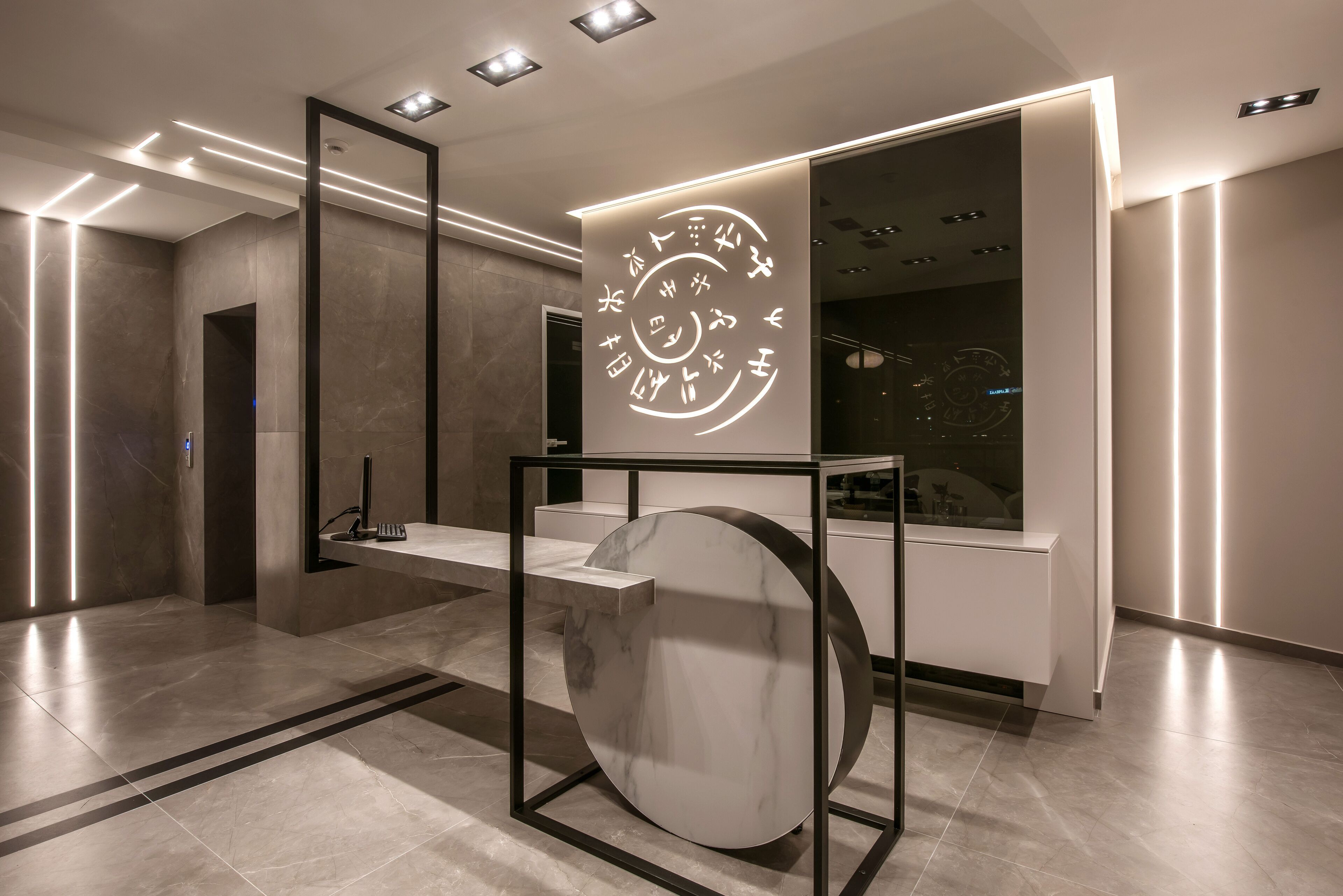 Eine moderne Lobby mit einer Marmor-Rezeption, einem großen, runden Wandkunstwerk und einem minimalistischen Design.