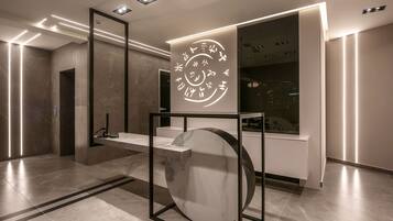 Un hall d’entrée moderne avec un comptoir de réception en marbre, une grande œuvre d’art murale de forme circulaire et un design minimaliste.
