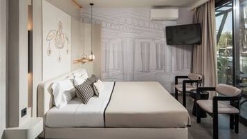 A modern hotel room with a large bed, a seating area with a table and chairs, a flat-screen TV mounted on the wall, and a large window offering a view of the outdoors.