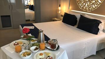 A hotel room with a neatly made bed, a breakfast table with various dishes, and a decorative wall piece.