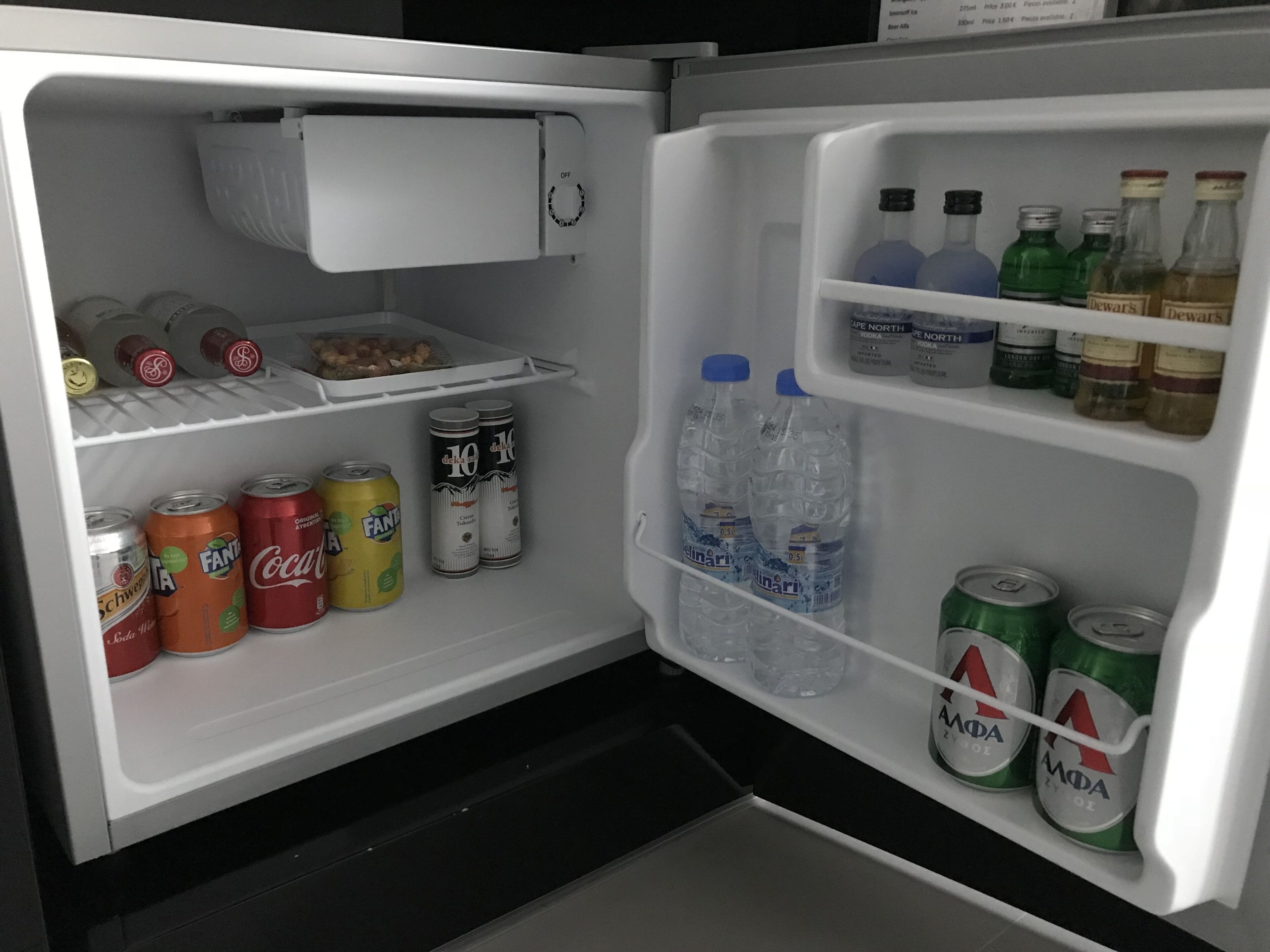 A refrigerator with shelves stocked with beverages, including cans and bottles.