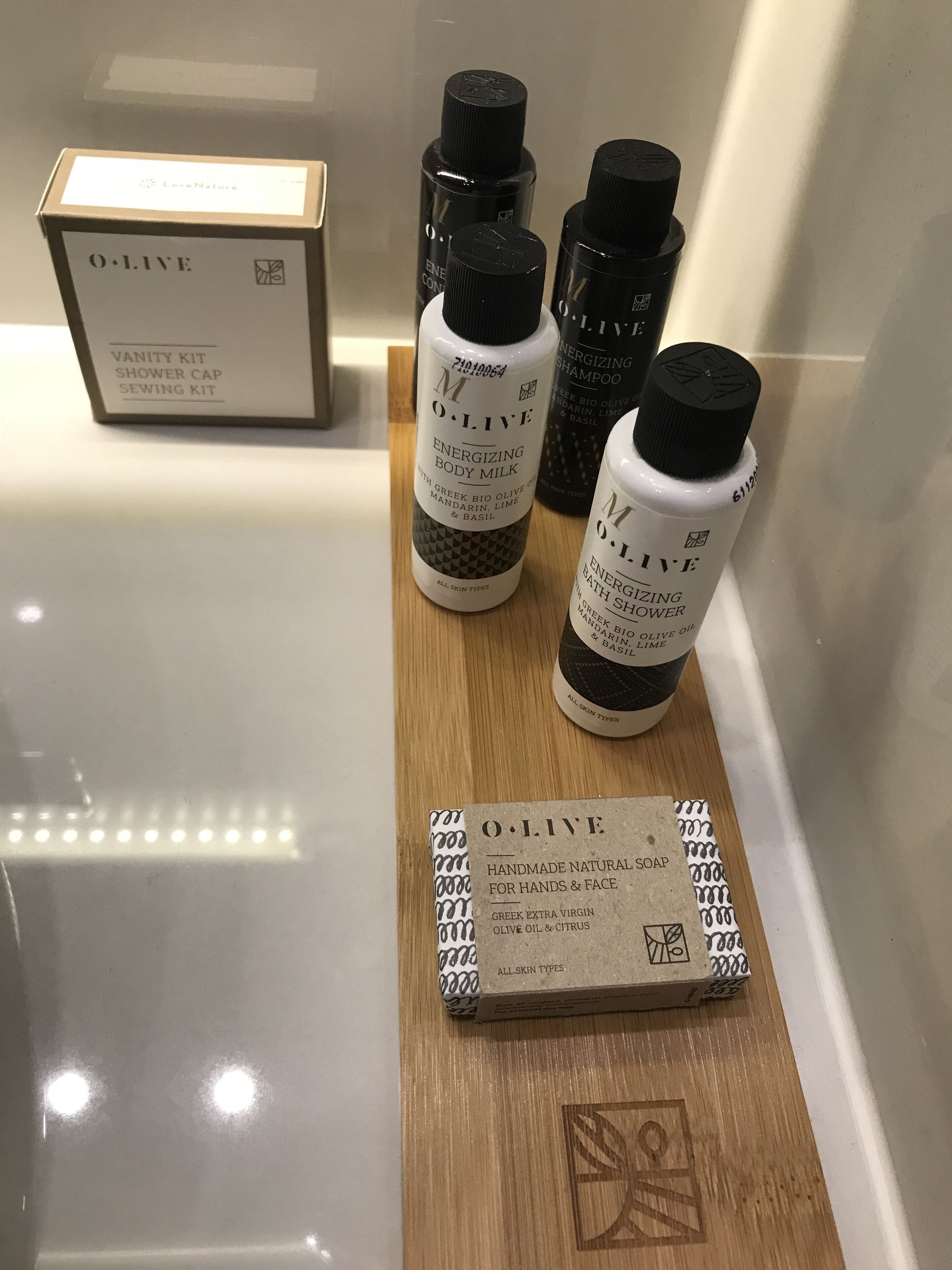 A vanity kit with a shower cap, sewing kit, and a box labeled "O. L. I. V. E." on a wooden surface.