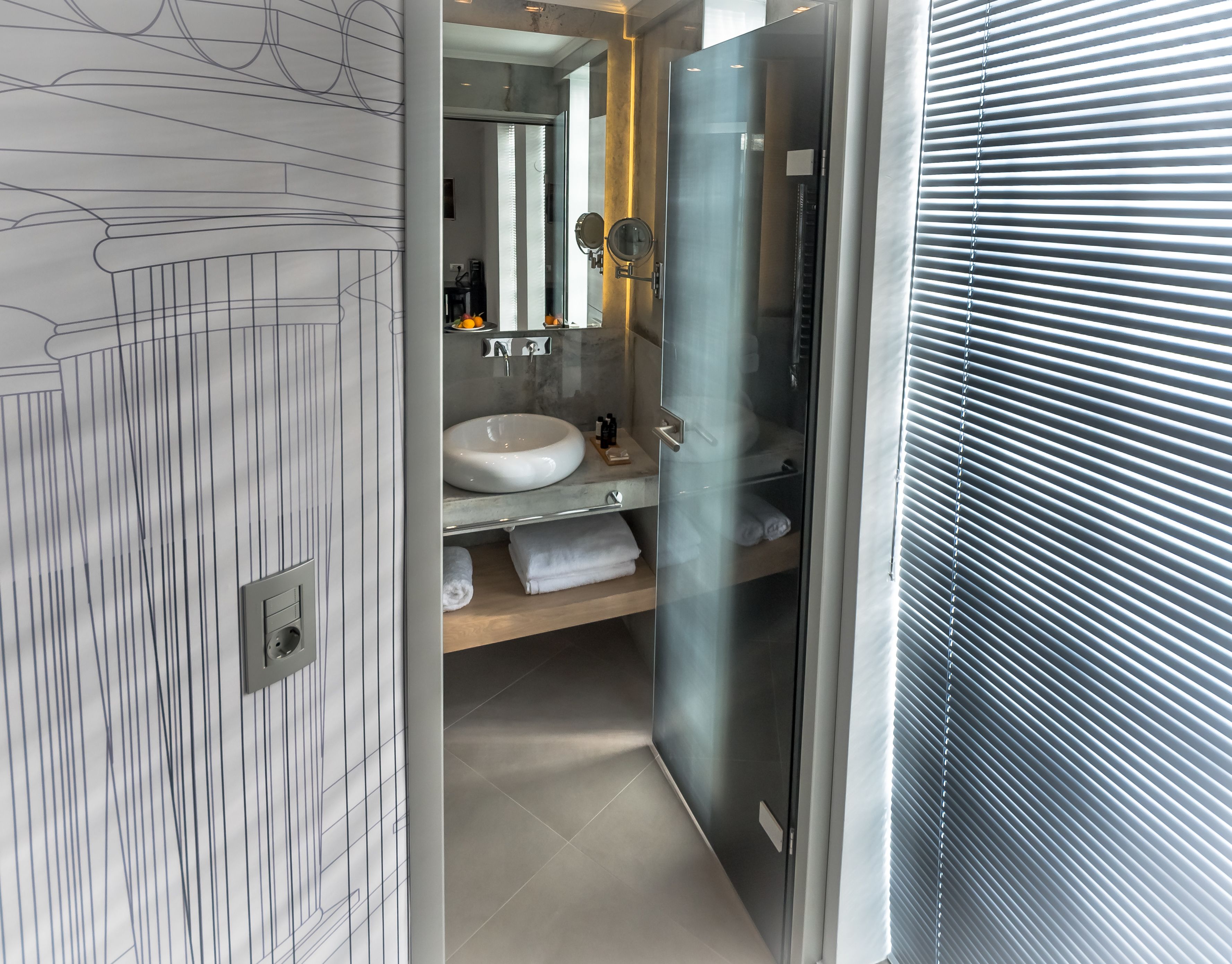 Een moderne badkamer met een marmeren wastafelmeubel, een douchecabine van glas en een grote spiegel.